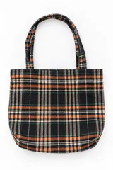 Bolso tipo tote bag con estampado a cuadros en tonos negro, naranja y blanco, con doble asa superior.