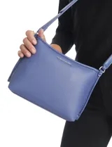 Cartera tipo bandolera Tahari color azul, con diseño estructurado y cierre metálico superior. Incluye una correa larga regulable y un mini monedero independiente enganchado a la misma. Presenta logo metálico frontal y herrajes plateados.