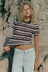Bermuda tipo jorts de denim en color celeste claro, con tiro medio, diseño de cinco bolsillos y cinturilla doblada. Presenta roturas decorativas en la parte delantera y cierre frontal con cremallera y botón metálico.