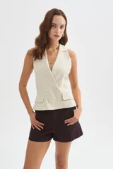 Chaleco sastrero beige de viscosa, con solapas, doble botonadura frontal y bolsillos con solapa en los laterales.