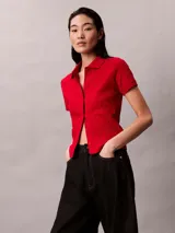 Chomba roja de Calvin Klein confeccionada en algodón con textura jacquard y estampado integral del logo. Cuenta con cuello polo, manga corta, cierre frontal con botones y detalles acanalados en los puños y el dobladillo.