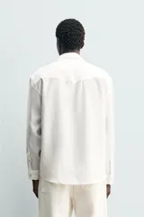 Camisa de corte regular confeccionada en tejido con mezcla de lyocell, con cuello solapa, manga larga con puños abotonados y cierre frontal de botones.