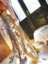 Pollera larga dorada de lentejuelas con cintura dorada y tajo lateral.