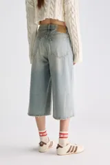 Jean culotte estilo bermuda de tiro bajo, color celeste con efecto desgastado, perneras amplias y corte recto por debajo de las rodillas.