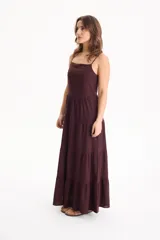 Vestido largo color blanco, confeccionado en lino, con tiras finas regulables, escote recto y falda amplia de corte acampanado con volados escalonados.