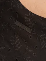 Vestido corto color crema con bordado de lunares negros, sin mangas y con escote redondo.