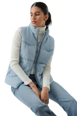 Chaleco acolchado tipo puffer con diseño western, confeccionado en denim de lavado claro. Presenta cuello alto, cierre frontal con cremallera y costuras horizontales.