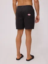 Short de baño tipo volley color negro, con cintura elástica y cordón ajustable en color crudo. Presenta un pequeño logo bordado en la parte inferior de la pierna derecha.