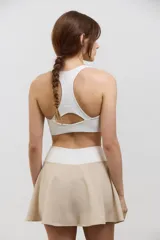 Pollera deportiva de corte acampanado color beige, con calza corta integrada de color blanco. Presenta cintura ancha de tiro alto y bolsillo invertido en la calza para guardar pelotas.