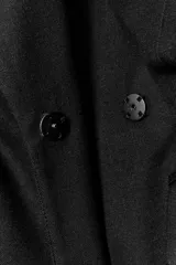 Blazer de cuello solapa y manga larga con hombreras marcadas. Presenta un diseño cruzado con cierre frontal de botones a presión, bolsillos delanteros con solapa y un detalle de cintura entallada con efecto abullonado.