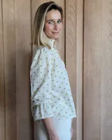 Blusa de algodón con cuello mao y volados, mangas largas con puños elásticos y corte holgado.