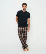 Pijama masculino compuesto por una remera negra de manga corta con cuello henley y botones, y un pantalón largo con estampado de cuadros en tonos marrones, negros y blancos.