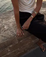 Anillo plateado con forma orgánica irregular y un agujero en el centro.