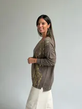 Sweater de punto color verde seco con estampado de salpicaduras en color dorado, cuello en V y mangas largas.
