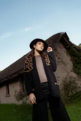 Saco tejido de punto con diseño de guarda inca en la parte superior. Presenta bolsillos frontales con detalles de tiras de cuero y flecos. De corte recto y largo medio, con terminaciones en tejido acanalado.