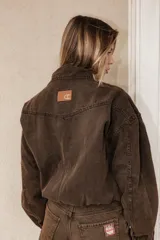 Campera de jean en color marrón chocolate con efecto lavado, corte semi oversized, cierre frontal metálico, cuello clásico y bolsillos laterales.