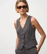 Chaleco sastre gris oscuro, ajustado al cuerpo, con escote en V, cierre frontal de cuatro botones y bolsillos embutidos.