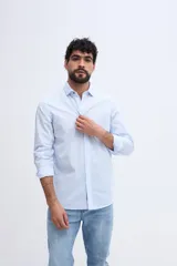 Camisa de manga larga fit semi slim color celeste, con cierre frontal de botones y cuello camisero clásico.