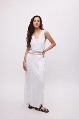 Top blanco de algodón con escote en V y tiras decorativas cruzadas en el frente.