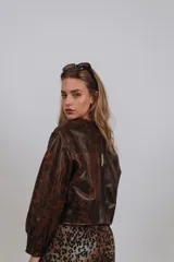 Campera bomber de cuero color marrón, con mangas abullonadas, puños elásticos y cierre frontal con botones a presión.