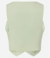Chaleco de crepe color verde menta con escote en V profundo, sin mangas, bolsillos o falsas solapas con botones dorados y ruedo asimétrico en punta.