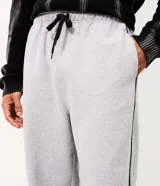 Pantalón de algodón color gris jaspeado, de corte wide leg amplio y recto, con cintura elástica y cordón de ajuste. Cuenta con bolsillos funcionales y detalle de filete lateral en color negro.