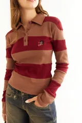 Top de manga larga con diseño de rayas horizontales en tonos negro y marrón, cuello polo con cierre de botones y bordado pequeño en el pecho.