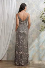 Vestido largo de fiesta color gris con escote en V, tirantes finos y tajo lateral. Presenta un diseño bordado con lentejuelas y brillos en toda la prenda.