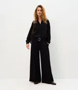 Pantalón wide leg negro con diseño a rayas sutiles, tiro medio, pinzas frontales y caída fluida.