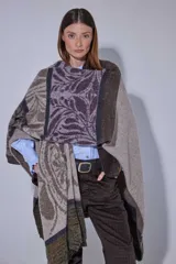 Ruana tejida en lana lambswool con diseño de bloques de color y tramas geométricas. Presenta cierre frontal con doble cursor y tiradores de cuero, permitiendo diferentes formas de uso.