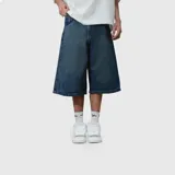 Bermuda de jean estilo baggy, color azul oscuro con efecto lavado. Presenta un corte holgado, bolsillos traseros amplios y un bordado decorativo con diseño de llamas y texto en uno de los bolsillos.