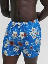 Short de baño para hombre, color azul vibrante, con estampado floral tropical en tonos blanco, crema y marrón rojizo. Presenta cintura elástica con cordón de ajuste blanco y un pequeño logo rectangular de la marca en la parte inferior derecha.