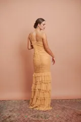 Vestido largo de fiesta color tostado, con escote en V, tirantes finos, cuerpo drapeado y falda sirena con múltiples volados en cascada.