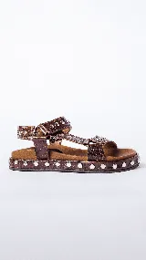 Sandalias de cuero marrón con estampado de cocodrilo y plataforma con tachas plateadas.