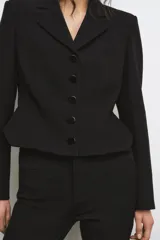 Blazer corta negra de la colección Zara Woman, con cuello solapa de muescas y manga larga. Presenta detalles de pespuntes marcados y forro interior a tono. Cierre frontal con botones.