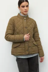 Campera capitoneada color beige, de cuello alto, con bolsillos de solapa y botones metálicos.