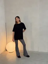 Conjunto compuesto por un remerón negro de corte holgado con aberturas laterales y un pantalón de tiro alto con diseño acampanado y estampado de lunares blancos sobre fondo negro.