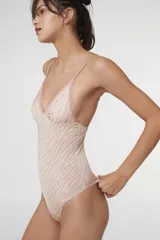 Body colaless de microfibra gloss con estampado de cebra en tonos beige y rosado. Presenta copas triangulares con bordes de puntilla, relleno extraíble, cierre en la entrepierna con broches de presión y breteles ajustables.