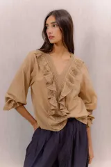 Camisa blanca de algodón con escote en V, volados delanteros con detalles de encaje y mangas largas con puños fruncidos.
