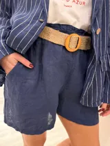 Short de lino color rojo, con cintura elástica y cinturón de rafia con hebilla circular.