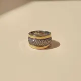 Anillo ancho de diseño bicolor, con bordes en oro y banda central de plata pavimentada con circonias brillantes.