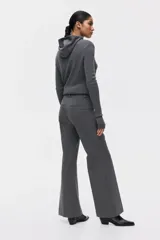 Pantalón sastrero de tiro alto con corte acampanado y pliegues frontales. Cuenta con cierre de botón y bolsillos decorativos.