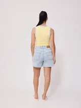 Musculosa crop amarilla con estampado de flor roja en el frente y ribetes grises en cuello y sisas, de la marca Rusty.