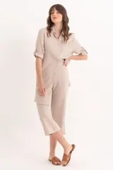 Pantalon palazzo de corte recto y tiro alto, confeccionado en lino color beige, con cierre frontal y bolsillos laterales.