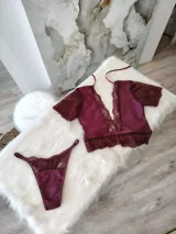 Conjunto de lencería compuesto por un top de encaje y satén con escote profundo y una tanga regulable a juego. El top presenta mangas cortas de encaje, detalles de puntilla en el escote y bajo, y cierre posterior. La tanga cuenta con detalles de encaje y forro de algodón.