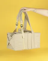 Bolso tipo tote color beige con diseño acolchado y doble asa de hombro.