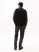 Chaleco negro de lona de algodón con cuello de punto canalé y cierre de cremallera. Tiene dos bolsillos ribeteados delanteros, un bolsillo interior de parche y parche de Tommy en el pecho.