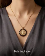 Collar de acero con baño de oro, con cadena fina y medalla colgante de San Benito rodeada por cristales negros facetados.