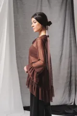 Blusa de tul marrón semitransparente, de corte holgado y asimétrico, con mangas largas abullonadas terminadas en volados y detalle de lazada en el cuello.