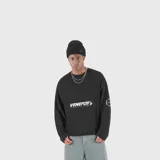 Buzo negro de manga larga, con cuello redondo y diseño holgado. Cuenta con estampado tipográfico blanco en el pecho y en la manga.